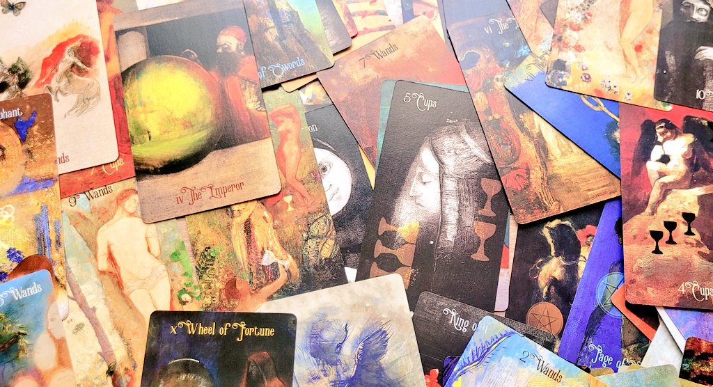 The lonely dreamer troisi&egrave;me &eacute;dition. Sur du parquet qui est peu visible, des cartes de tarot (plus grandes que des cartes &agrave; jouer), au touch&eacute; l&eacute;g&egrave;rement tiss&eacute;, brillant sans l&rsquo;&ecirc;tre. Les cartes ne repr&eacute;sentent pas les motifs du rider waite traditionnel mais les peintures d&rsquo;odilon redon,( multicolores, myst&eacute;rieuses, dans un style symboliste (qui prend un peu des jeux de couleurs de l&rsquo;impressionnisme tout en accordant de l&rsquo;importance aux d&eacute;tails et &agrave; une ambiance mystique, inspir&eacute;e de la mythologie et du folklore gr&eacute;co-romain, fantastique et chr&eacute;tien), sont &eacute;parpill&eacute;es au sol sans que l&rsquo;une d&rsquo;entre elles ne ressorte particuli&egrave;rement