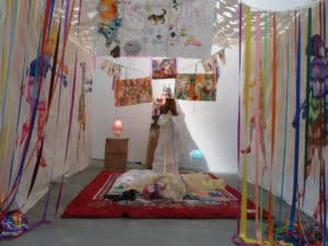 Une installation multicolore de procès tout en papier avec une vraie femme, une bougie et un message appelant à la vérité.